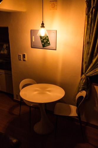 a table and chairs in a room with a light at Guest House Amakara Okinawa in Nago