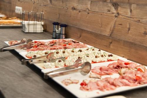 a buffet with several trays of food on a table at Hotel Alpenhof in Sankt Jakob in Defereggen