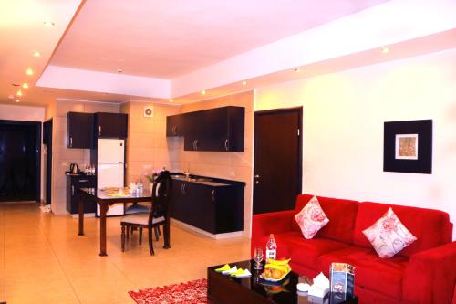 a living room with a red couch and a kitchen at City Rose Hotel Suites in Amman