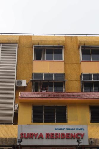 a yellow building with people looking out the window at Hotel Surya Residency Majestic in Bengaluru