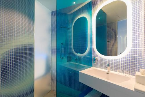 a bathroom with blue tiles and a sink and mirrors at Park Inn by Radisson Amsterdam City West in Amsterdam