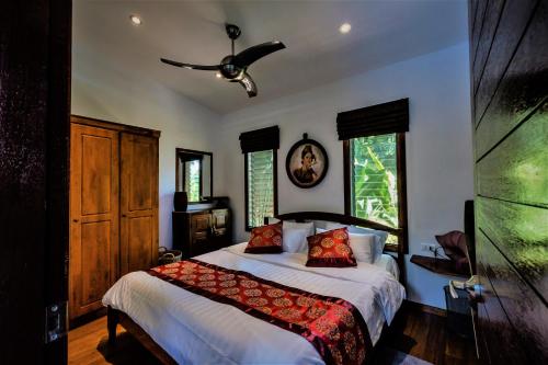 a bedroom with a bed and a ceiling fan at Stunning villa with ocean views and free car in Lamai