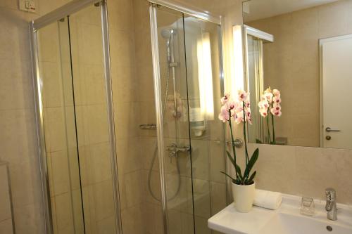 un bagno con doccia e un vaso di fiori su un lavandino di Hotel Draganic a Draganići