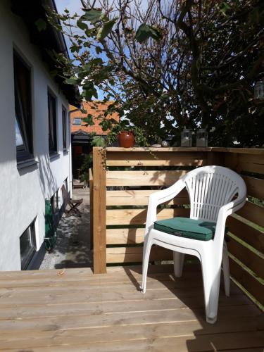 a white chair sitting on a wooden deck at Apartment Fanny fri adgang til svømmehal in Hvide Sande