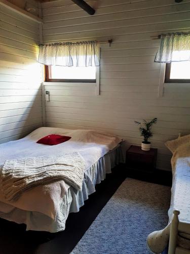 a bedroom with a bed in a room with two windows at Olkka ranch in Mustakulkkula