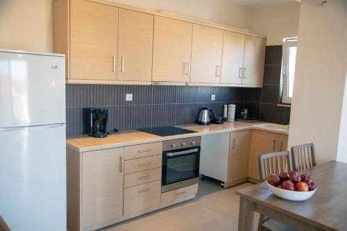 a kitchen with wooden cabinets and a bowl of fruit on a table at Catherine's Comfort Apartment Νο3 in Lavrio