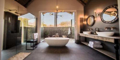 ein großes Badezimmer mit zwei Waschbecken und einer großen Badewanne in der Unterkunft Nkala Safari Lodge in Matlhagame