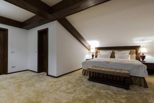 a bedroom with a large bed with white walls at Bran Monte Crai Chalet in Bran