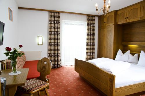 a hotel room with a bed and a desk and a table at Berghotel Rasis in Galtür