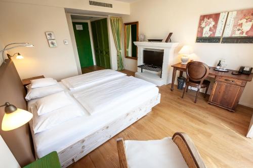 a bedroom with a bed and a desk and a fireplace at Hotel Hirschen in Freiburg-Lehen in Freiburg im Breisgau