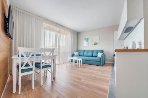a living room with a table and a blue couch at Wczasowa, Sun & Snow in Ustka
