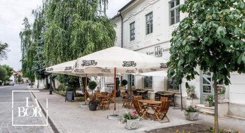 una cafetería al aire libre con mesas y sillas bajo una sombrilla en LaBor Kvártély, en Tokaj