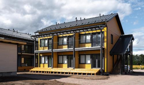 a yellow house with a black roof at Forenom Serviced Apartments Vantaa Jokiniemi in Vantaa