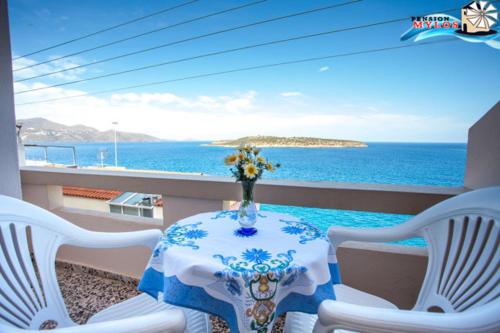 a table and chairs on a balcony with a view of the ocean at Pension Mylos in Agios Nikolaos