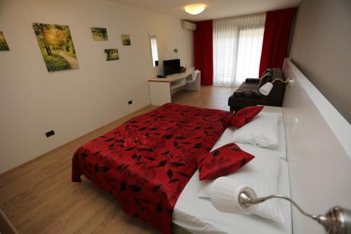 a bedroom with a bed with a red comforter at Hotel Ravna Gora in Ravna Gora