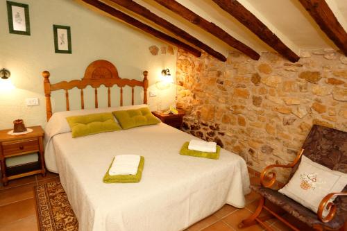 1 dormitorio con cama y pared de piedra en Casa Rural Mas de Sant Pau - Turistrat., en Albocácer