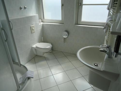 ein weißes Bad mit einem WC und einem Waschbecken in der Unterkunft Hotel und Rasthof AVUS in Berlin
