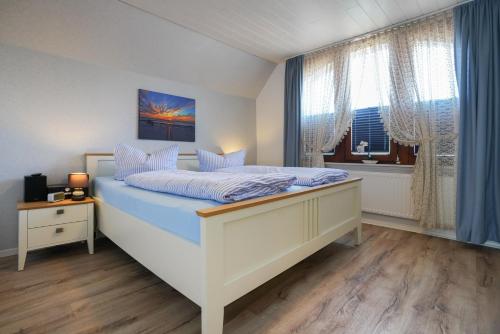 a bedroom with a bed with blue sheets and a window at Ferienhaus Daheim in Borkum