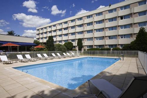 un hôtel avec une piscine, des chaises et un bâtiment dans l'établissement Novotel Paris Nord Expo Aulnay, à Aulnay-sous-Bois