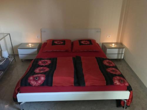 Un dormitorio con una cama roja con flores. en Moderne Ferienwohnung mit Traumseeblick Lago Maggiore, en Luino