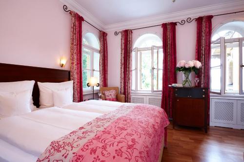 a bedroom with a large bed with red curtains at LA VILLA am Starnberger See in Niederpöcking