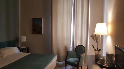 una camera con letto, sedia e lampada di B&B Metropolis a Livorno