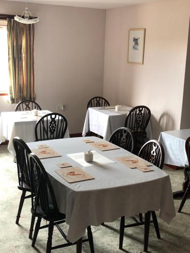 jadalnia z białymi stołami i czarnymi krzesłami w obiekcie Invernettie guesthouse w mieście Peterhead