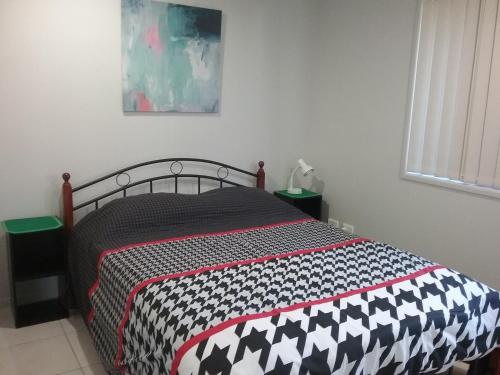 a bedroom with a bed with a black and white comforter at Banksia Apartment in Maryborough