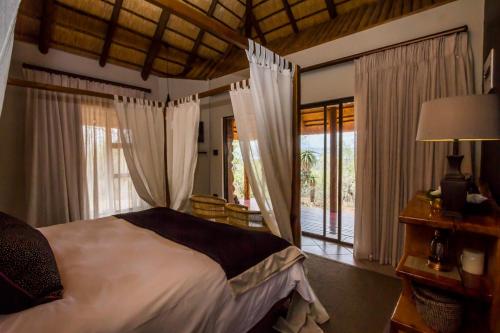 a bedroom with a bed and a large window at Mpeti Lodge in Mkuze