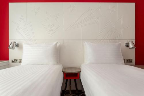 two beds with white sheets and a stool between them at ibis Styles Glasgow Central in Glasgow