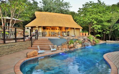 a resort with a pool and a thatched building at Victoria Falls Safari Club in Victoria Falls
