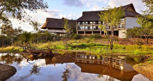 a house with a reflection in the water in front at Victoria Falls Safari Club in Victoria Falls