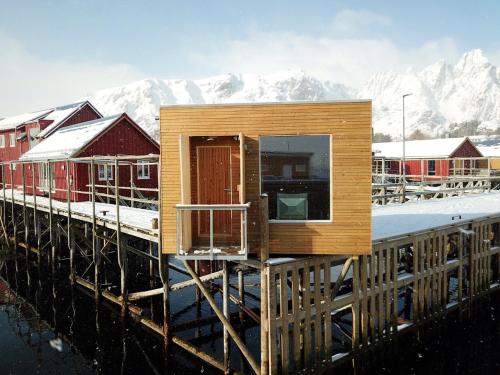 a tiny house on a dock with mountains in the background at Hattvika Lodge in Ballstad