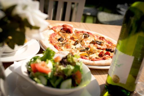 a table with a pizza and a salad and a bottle of wine at YHA Bristol in Bristol