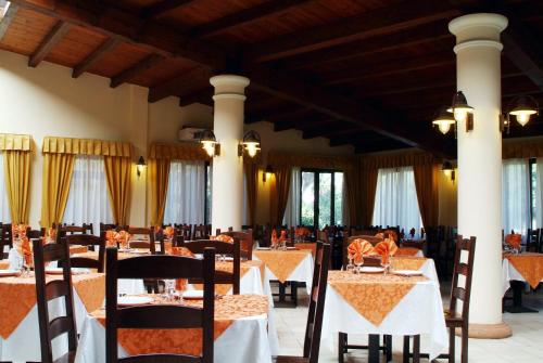 una sala da pranzo con tavoli, sedie e finestre di Hotel Fortezza ad Arborea