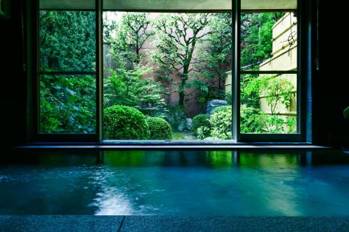 an empty room with an open window looking out at a garden at Yamadaya Ryokan in Kyoto