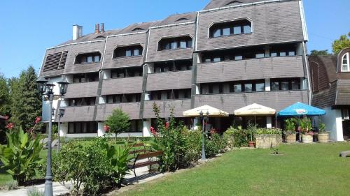 a large building with benches in front of it at Hotel Jogar in Balatonföldvár