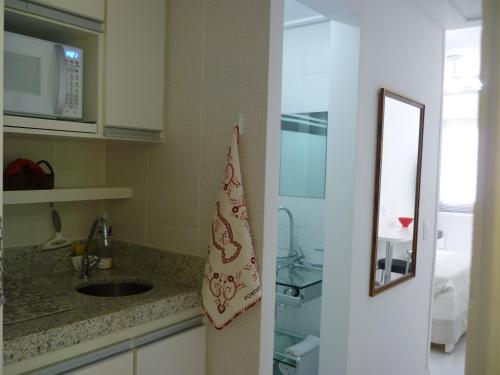 uma cozinha com um lavatório e um espelho em Flats Cavalinho Branco 405 ou 603 em Águas de Lindoia