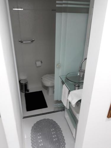 a bathroom with a toilet and a glass sink at Flats Cavalinho Branco 405 ou 603 in Águas de Lindoia
