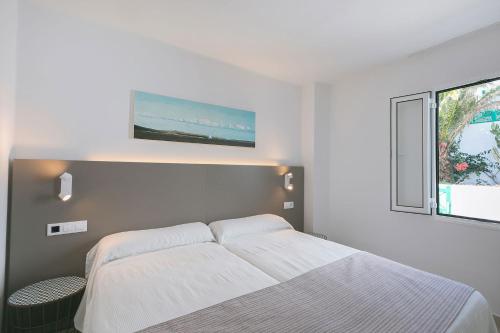 a white bedroom with a bed and a window at Apartamentos Celeste in Costa Teguise