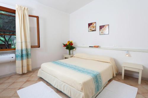 a white bedroom with a bed and a window at Hotel Fortezza in Arborea