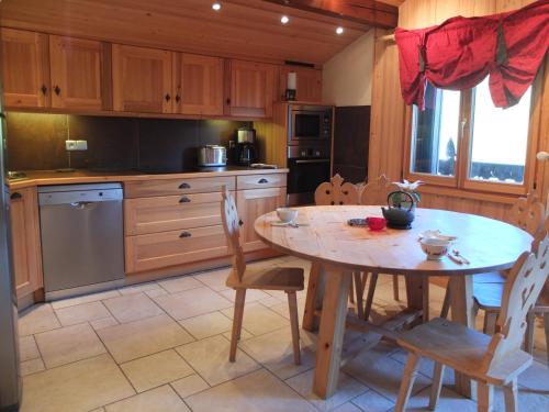 une cuisine avec une table en bois et une table et des chaises dans l'établissement Edelweiss, aux Gets