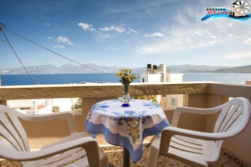 a table and chairs on a balcony with a view of the ocean at Pension Mylos in Agios Nikolaos