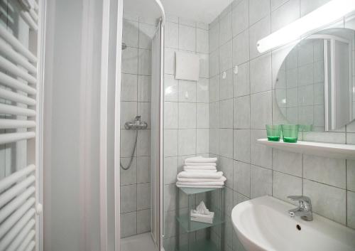 uma casa de banho branca com um chuveiro e um lavatório. em Fewo an der Seepromenade em Pertisau