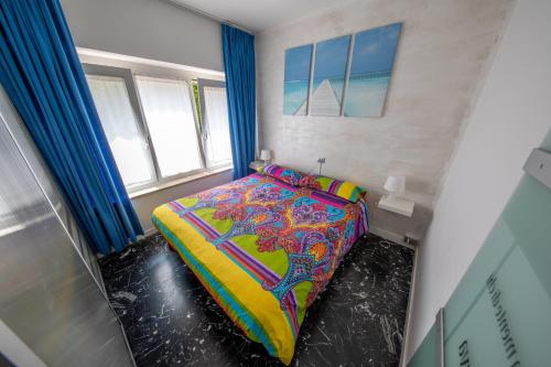 リーヴァ・デル・ガルダにあるAppartamento Silvyの小さなベッドルーム(カラフルな掛け布団付きのベッド1台付)
