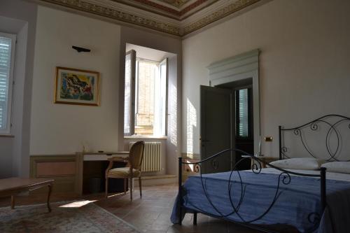 Schlafzimmer mit einem Bett, einem Schreibtisch und Fenstern in der Unterkunft Palazzo Roberti in Monte San Giusto