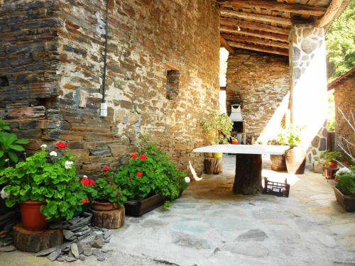 a patio with a table and flowers and a brick wall at Pensión Santa Rosa in Samos