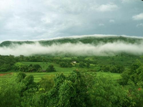 a foggy hillside with trees and clouds in the sky at Phurua Bussaba Resort & Spa in Loei