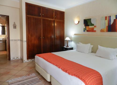 a bedroom with a large white bed with an orange blanket at Residencia Julio in Sagres
