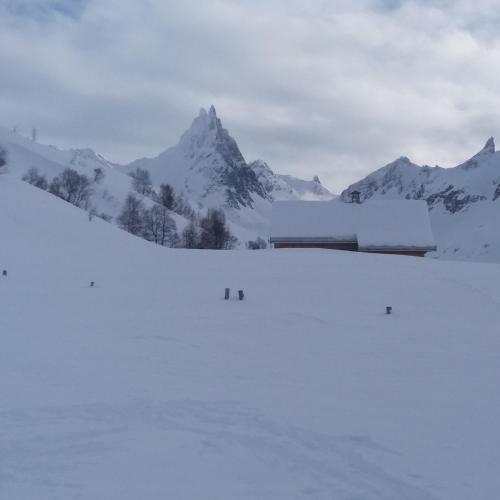 a snow covered mountain with a building in the distance at Aiguille Noire in Valloire